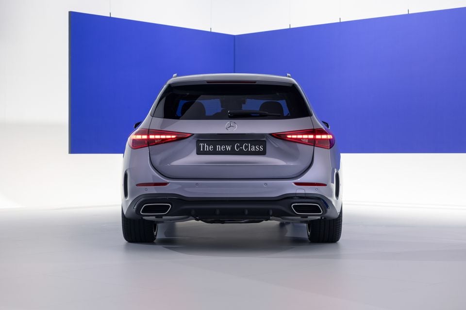 Rear view of a silver 2027 Mercedes-Benz C-Class wagon in a studio setting, showing LED tail lights, twin exhaust outlets and the three-pointed star badge.