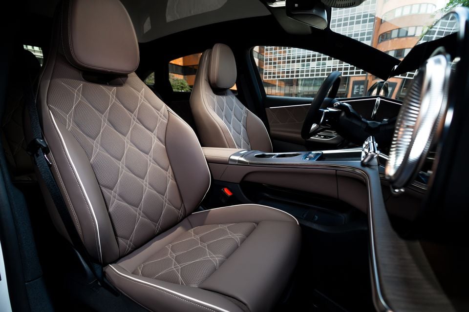 Quilted brown leather front seats of a Mercedes-Benz C-Class Electric, viewed from the passenger side door opening