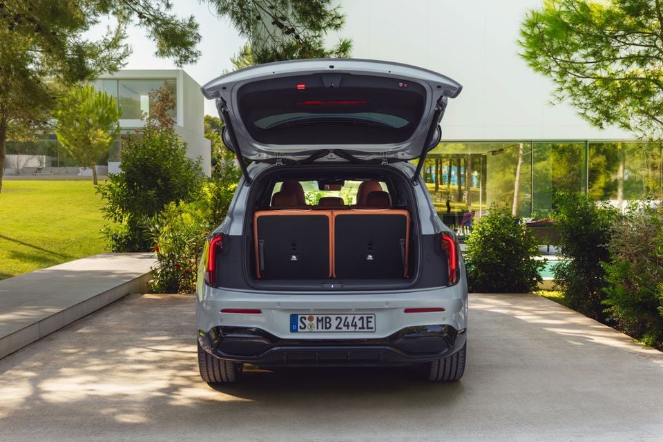 Rear view of a silver 2027 Mercedes-Benz GLB SUV with the tailgate open, revealing the boot and folded rear seats, parked in a modern driveway.