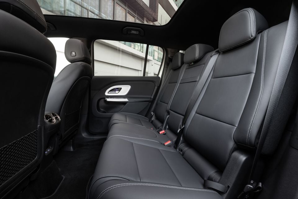 Black leather rear seats inside the 2027 Mercedes-Benz GLB 350 4Matic electric SUV, with a panoramic glass roof and rear air vents