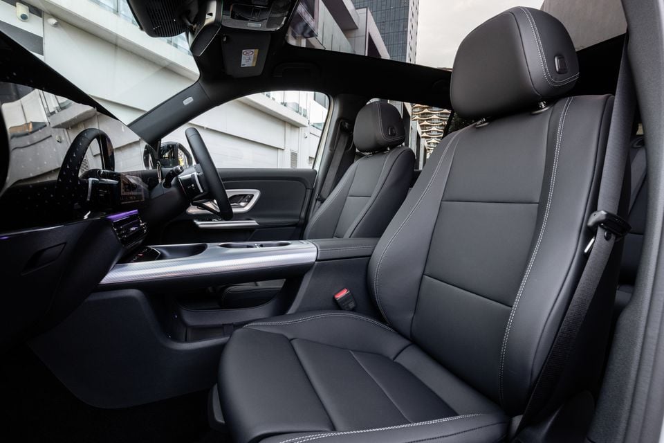 Black leather front seats, steering wheel and panoramic glass roof inside the 2027 Mercedes-Benz GLB 350 4Matic electric SUV, seen from the passenger door