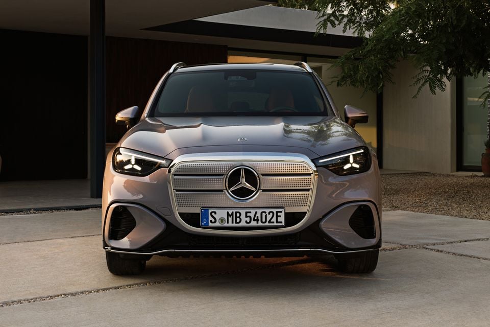 A 2027 Mercedes-Benz GLC 400 Electric SUV seen from the front, parked on a driveway outside a modern building