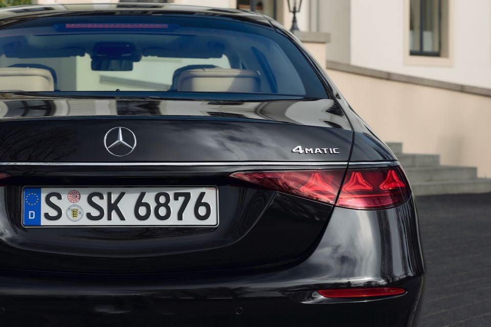 Close-up of the rear of a black Mercedes-Benz S-Class sedan, showing the badge, 4Matic emblem and taillight detail.