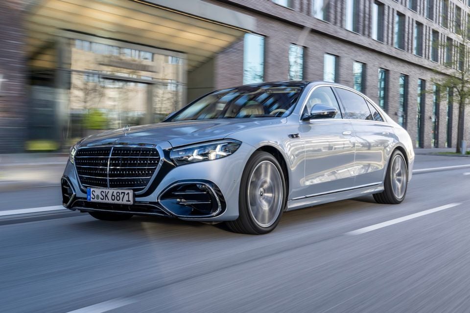 A silver Mercedes-Benz S-Class sedan driving on a city street, seen from the front quarter angle