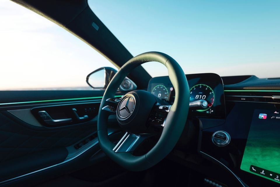 The steering wheel and digital instrument cluster inside a 2027 Mercedes-Benz S-Class, with the driver's side mirror and window visible.