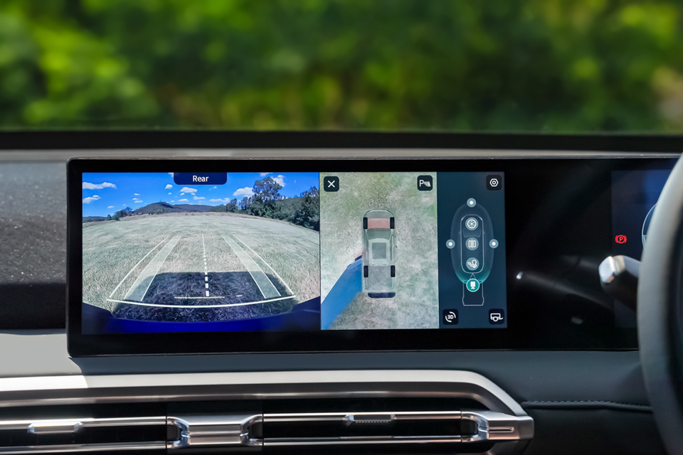 The 2027 MG U9 EV's widescreen infotainment display showing the rear-view camera and a 360-degree overhead parking view of the ute