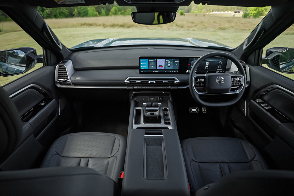 Dashboard and front cabin of the 2027 MG U9 EV ute, showing a wide touchscreen, digital driver display, steering wheel and dark grey leather front seats