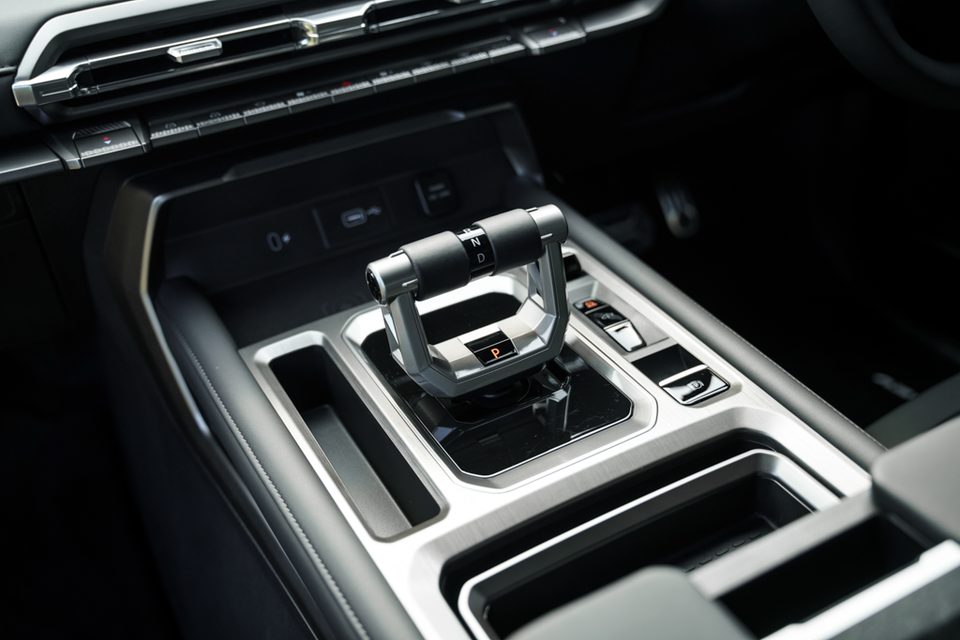Centre console of the 2027 MG U9 EV ute showing a chrome-framed gear selector set to park, storage trays and climate control buttons