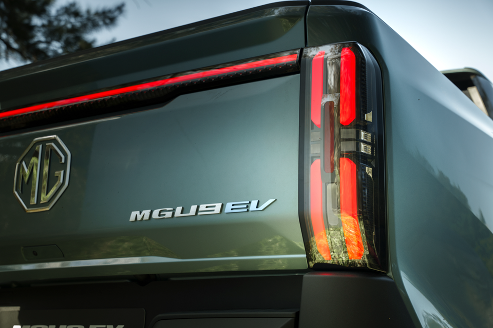 Close-up of the 2027 MG U9 EV ute's tailgate showing the MG badge, MGU9 EV lettering and illuminated red tail-light in green paint