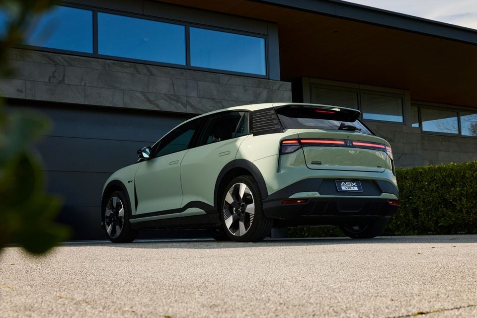 A pale green 2027 Mitsubishi ASX VR-e SUV, an electric vehicle, parked in a driveway seen from the rear quarter