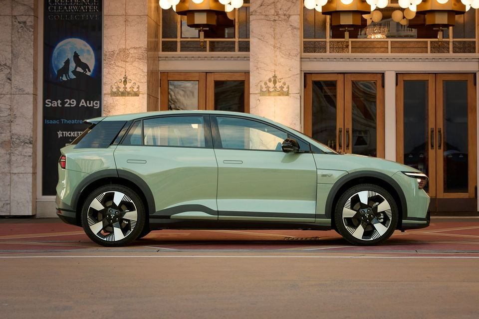 A pale green 2027 Mitsubishi ASX VR-e electric SUV parked side-on outside a theatre building at dusk.