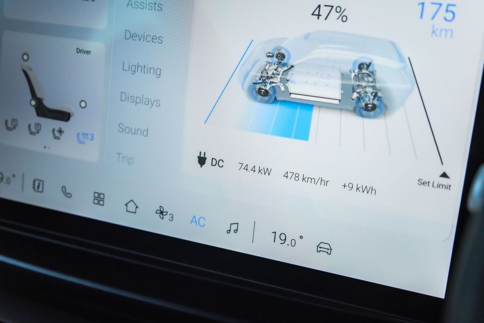 A close-up of an electric vehicle's touchscreen showing battery charge level, driving range and a DC fast-charging status diagram.
