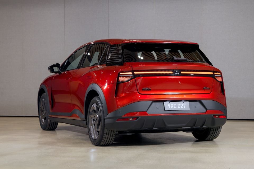 Um SUV elétrico Mitsubishi ASX VR-e Aspire 2027 vermelho estacionado em um estúdio, visto do lado traseiro do motorista