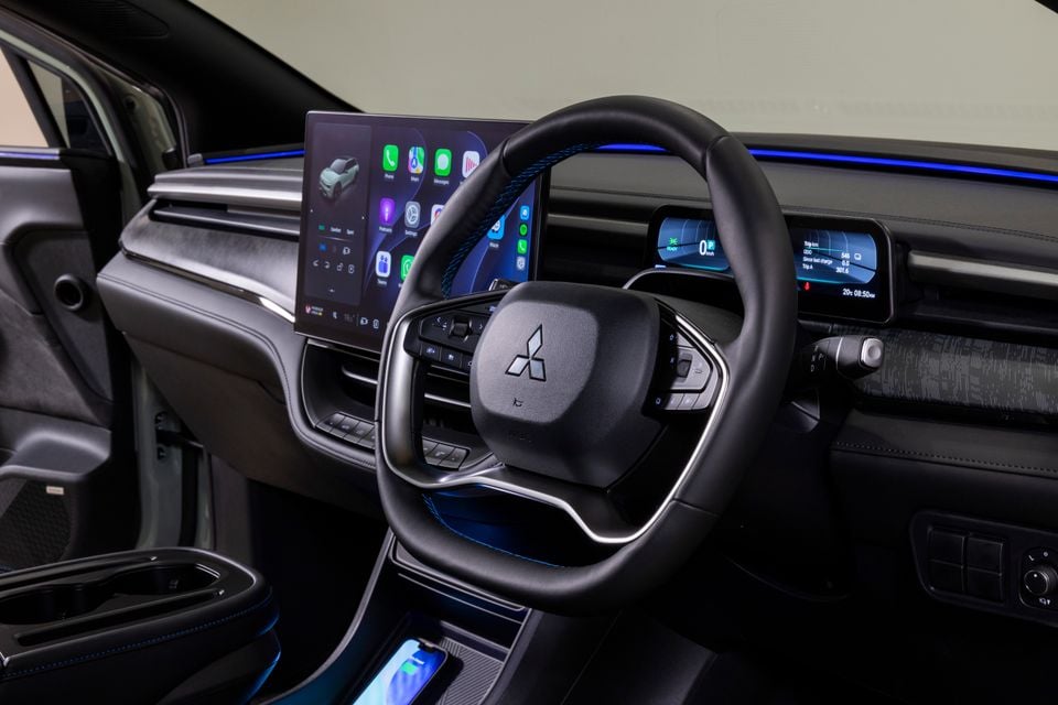 Dashboard of the 2027 Mitsubishi ASX electric SUV showing the steering wheel, digital instrument cluster, large central touchscreen and blue ambient lighting