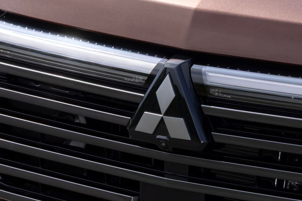 Close-up of the Mitsubishi badge on the grille of a bronze-coloured vehicle, likely the upcoming Pajero