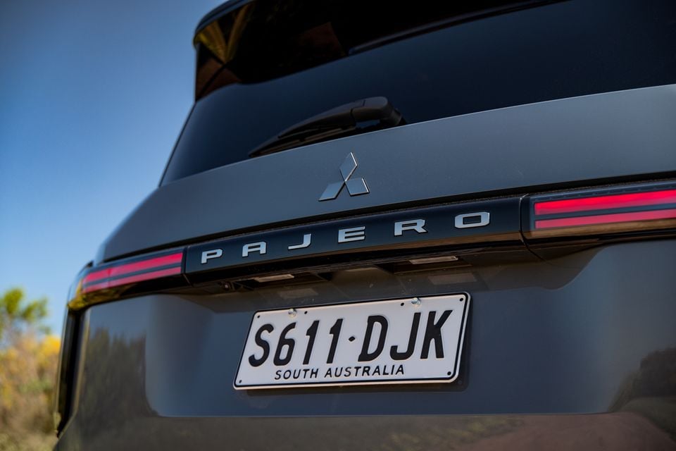 Rear tailgate of a dark grey 2027 Mitsubishi Pajero showing the Pajero lettering, Mitsubishi badge, full-width tail-lights and South Australian number plate