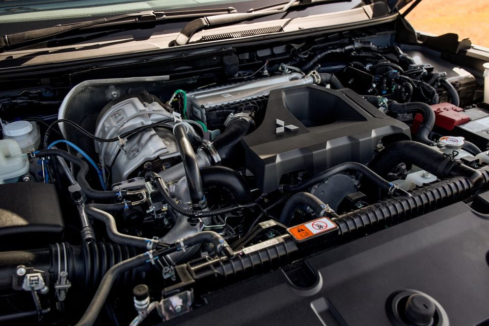 Turbo-diesel engine bay of the 2027 Mitsubishi Pajero with the bonnet open, showing the engine cover with Mitsubishi logo and turbocharger