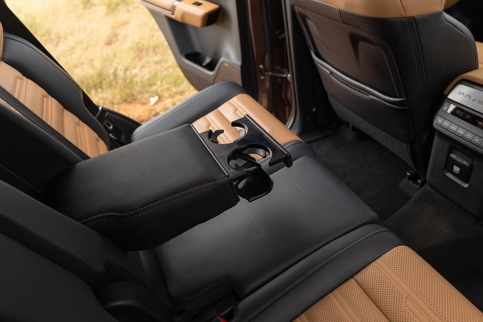 Rear seats of the 2027 Mitsubishi Pajero with a fold-down centre armrest and cupholders, black and tan leather trim and rear climate controls