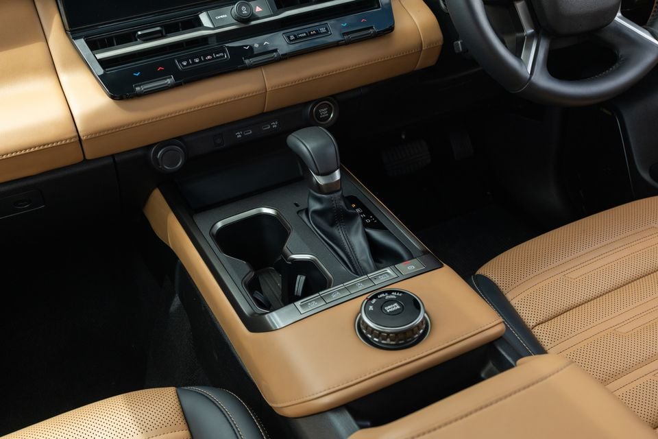 Centre console of the 2027 Mitsubishi Pajero with tan leather trim, gear selector, cupholders, drive mode dial and climate controls