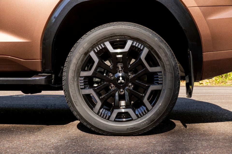 Close-up of a black alloy wheel with Bridgestone tyre on a bronze Mitsubishi Pajero SUV