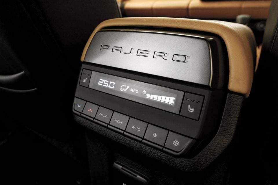 Rear climate control panel in the Mitsubishi Pajero, showing temperature set to 25.0 degrees with AUTO mode and heated seat controls, branded with 'Pajero' lettering