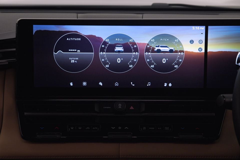 The infotainment touchscreen of a 2027 Mitsubishi Pajero displaying off-road gauges including altitude, roll, and pitch meters, alongside climate control buttons below.