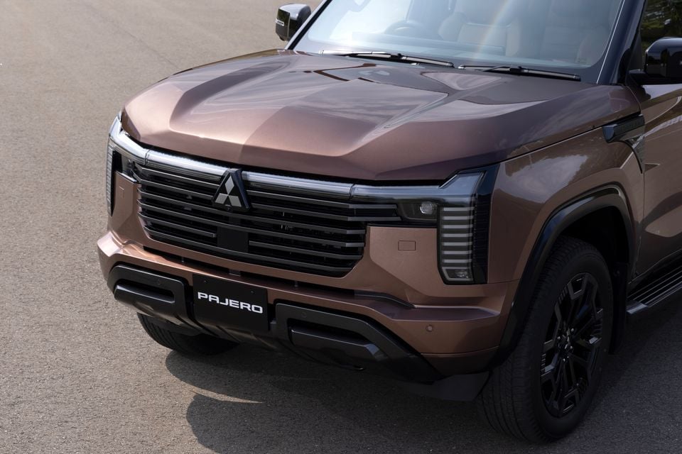 Front view of a brown Mitsubishi Pajero SUV showing its bold grille, Mitsubishi badge, and angular headlights