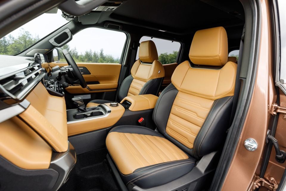 Interior of the 2027 Mitsubishi Pajero showing tan and black leather front seats, centre console, and dashboard with large touchscreen