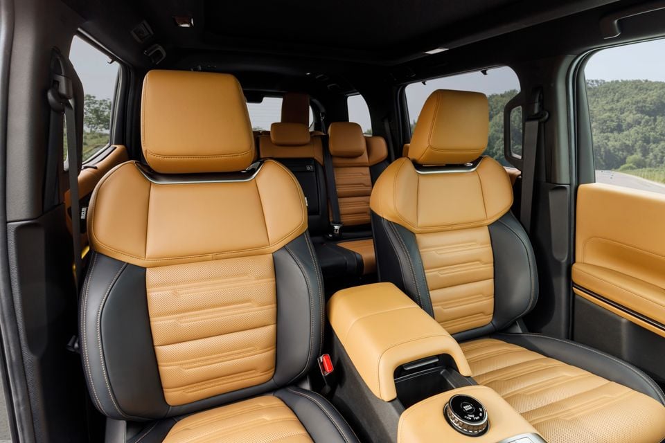 Two-tone tan and black leather front seats of the 2027 Mitsubishi Pajero SUV, with second and third row seating visible behind