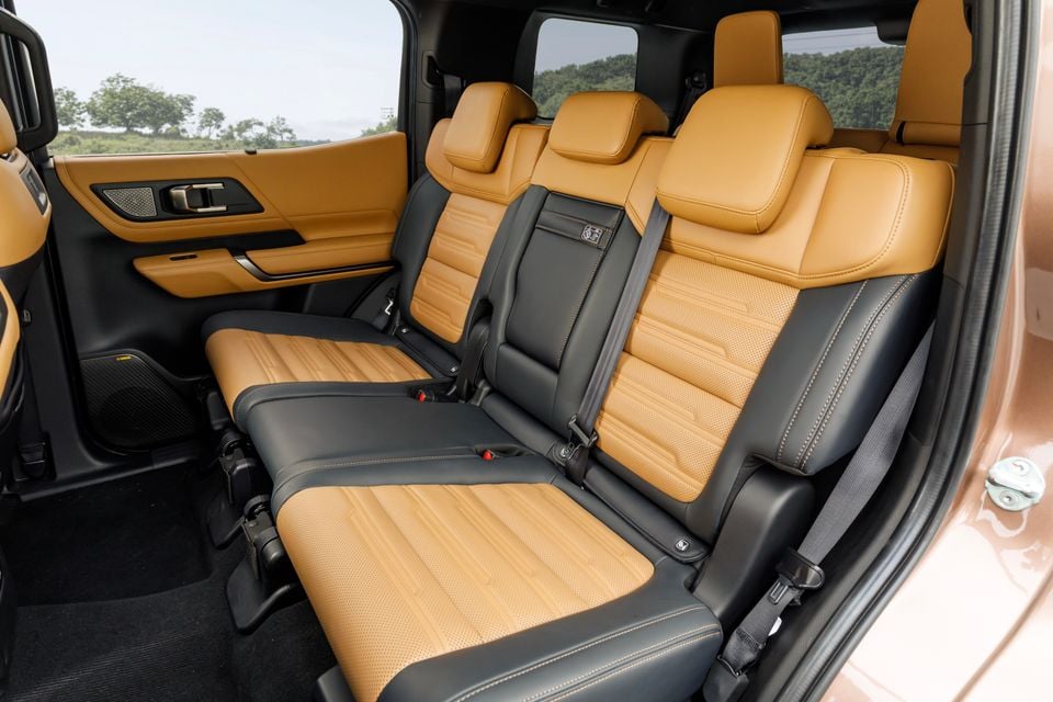 Tan and black two-tone leather rear seats inside the 2027 Mitsubishi Pajero, viewed from the open side door