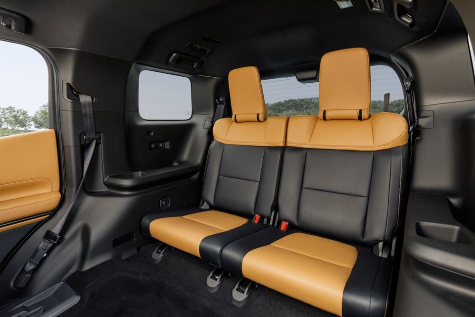 Two-tone tan and black leather rear seats inside the 2027 Mitsubishi Pajero, viewed from the third row looking forward