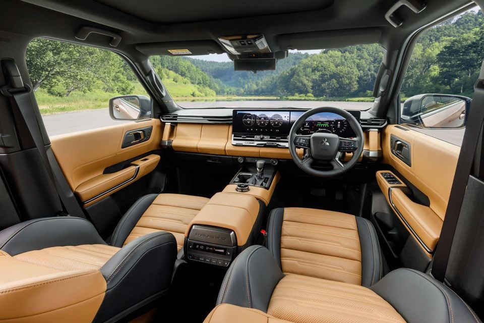 Interior of the 2027 Mitsubishi Pajero showing tan and black leather seats, a wide digital display dashboard, and a right-hand drive layout