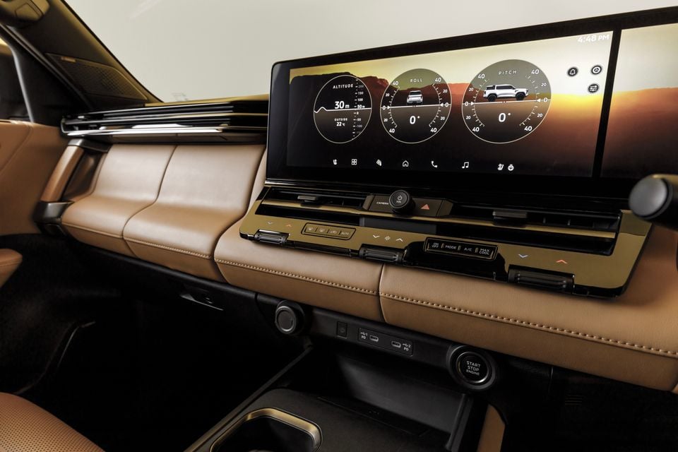 Interior of the 2027 Mitsubishi Pajero showing a large widescreen infotainment display with off-road data including altitude, roll and pitch gauges, surrounded by tan leather trim and a central control panel