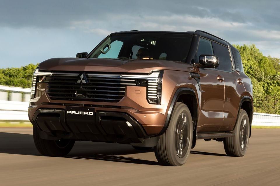 A bronze Mitsubishi Pajero SUV driving on a track, seen from the front at a slight angle