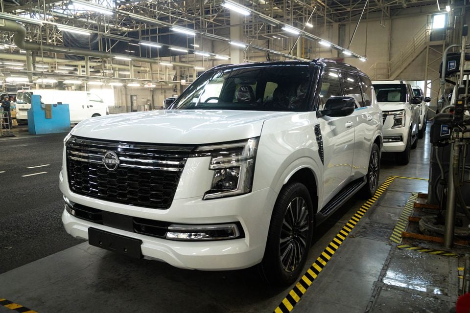 A white 2027 Nissan Patrol SUV seen from the front on a factory production line, with more Patrols lined up behind it