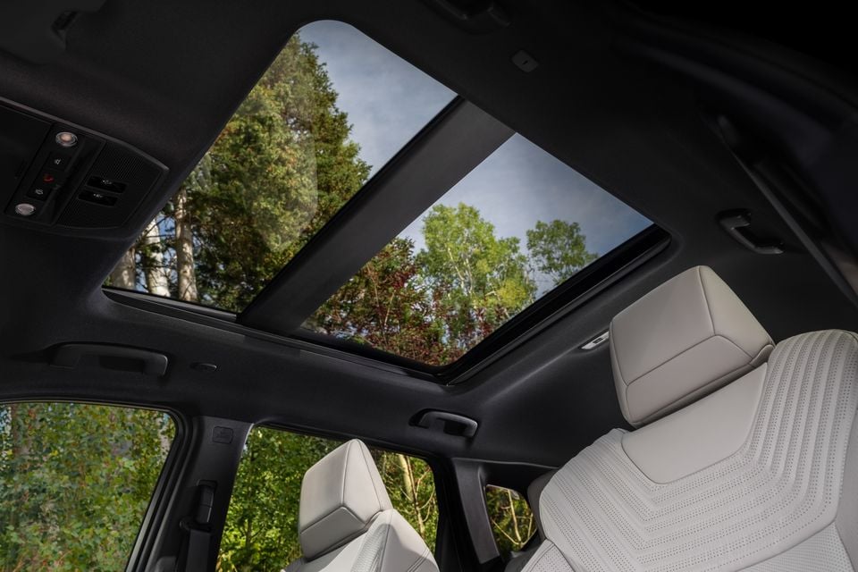 Interior view of the 2027 Nissan Rogue Hybrid showing a large panoramic sunroof, light grey perforated leather rear seats, and overhead controls