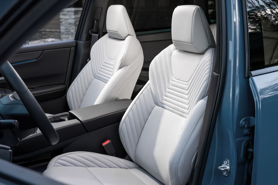 White leather front seats with quilted stitching detail inside a 2027 Nissan Rogue Hybrid, viewed through the open passenger door