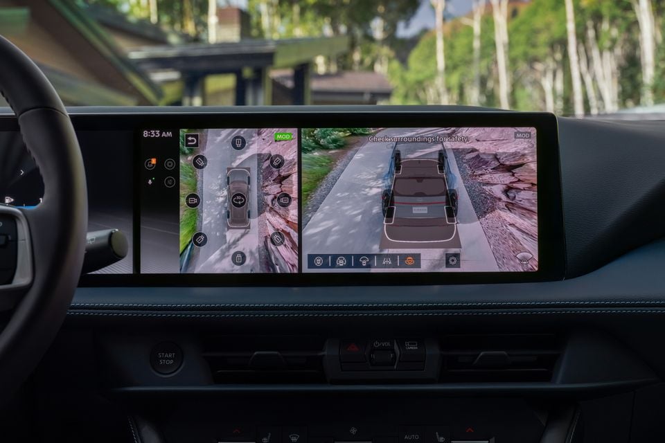 The infotainment screen of a 2027 Nissan Rogue Hybrid displaying a 360-degree surround-view camera system with a bird's-eye view and rear camera feed on an off-road trail
