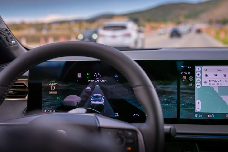 Interior view of a Nissan Rogue Hybrid showing the digital instrument cluster displaying ProPILOT Assist active at 45 mph, with a touchscreen infotainment system showing Google Maps, while driving on a highway with traffic ahead