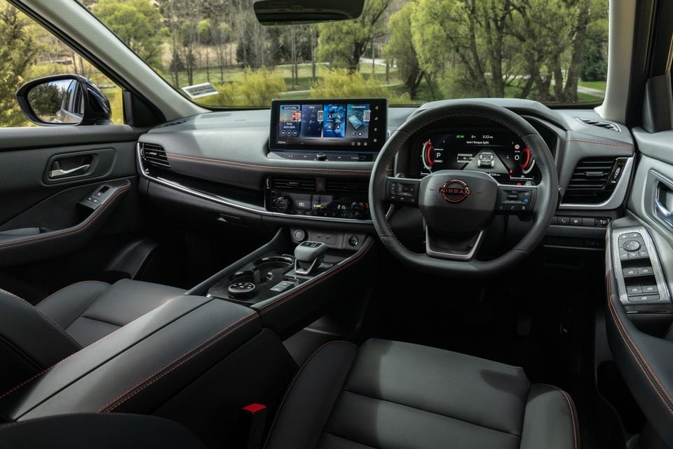 The black leather interior of a 2027 Nissan X-Trail Rock Creek, showing the dashboard, steering wheel and infotainment screen.