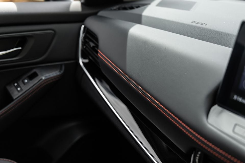 Close-up of the dashboard and door trim inside a Nissan X-Trail Rock Creek, showing grey and black panels with red contrast stitching.