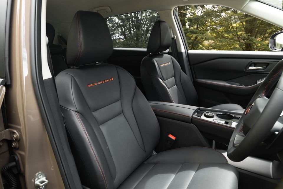 The black leather front seats with "Rock Creek" embroidery inside a 2027 Nissan X-Trail Rock Creek, viewed from the open driver's door.