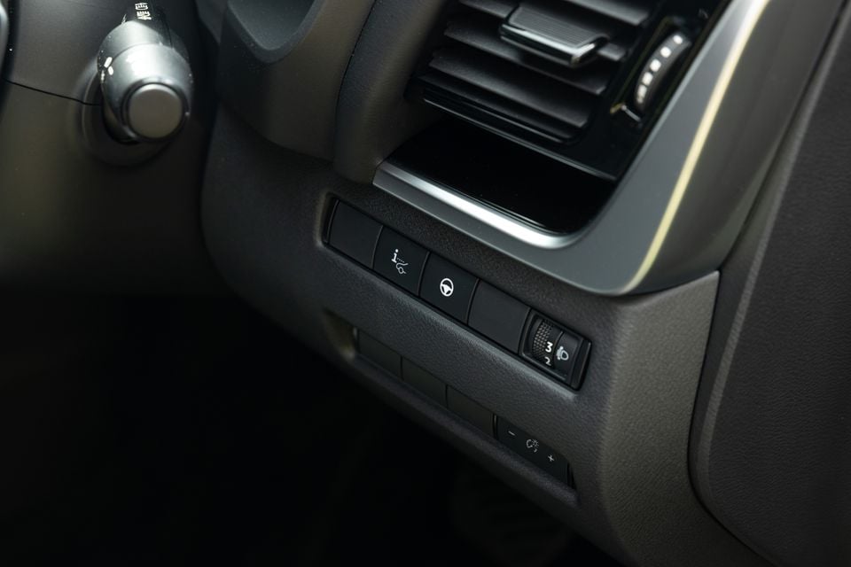 Close-up of dashboard controls including headlight dimmer dial and steering wheel settings buttons in a 2027 Nissan X-Trail