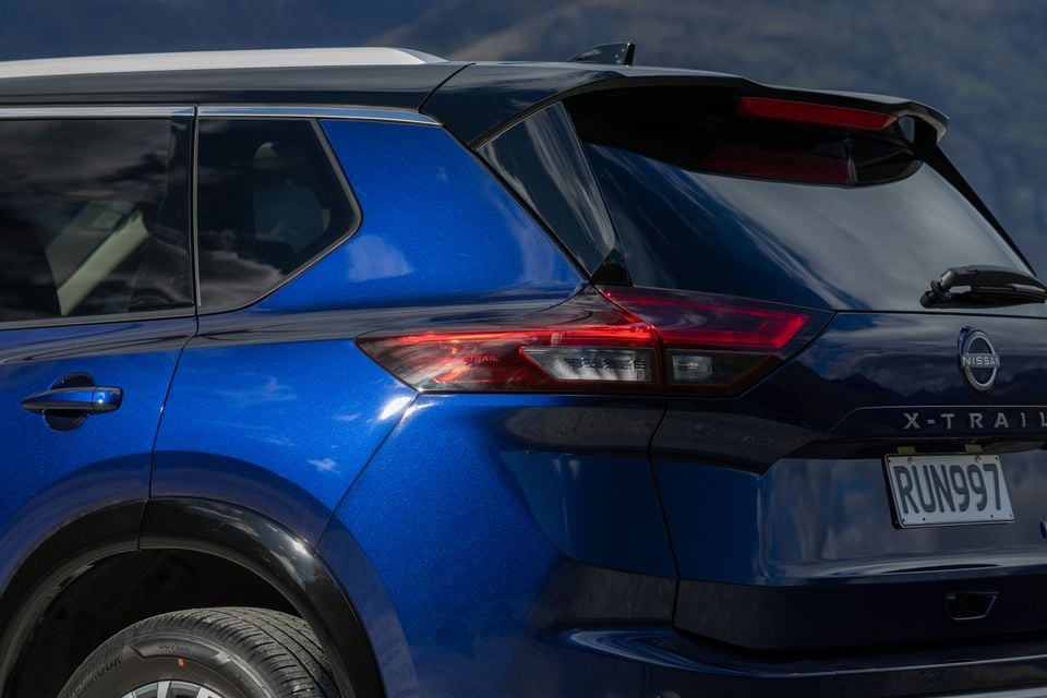 Close-up of the rear taillight and badge on a blue Nissan X-Trail SUV