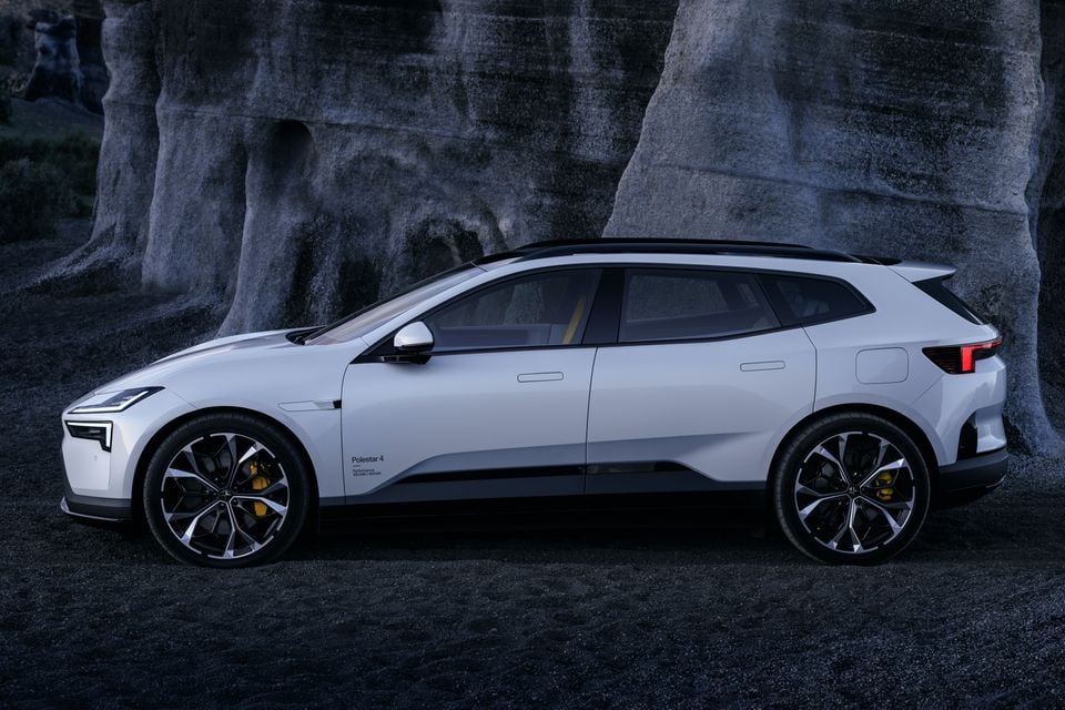 A white Polestar 4 SUV seen from the side, parked in front of a rocky stone backdrop