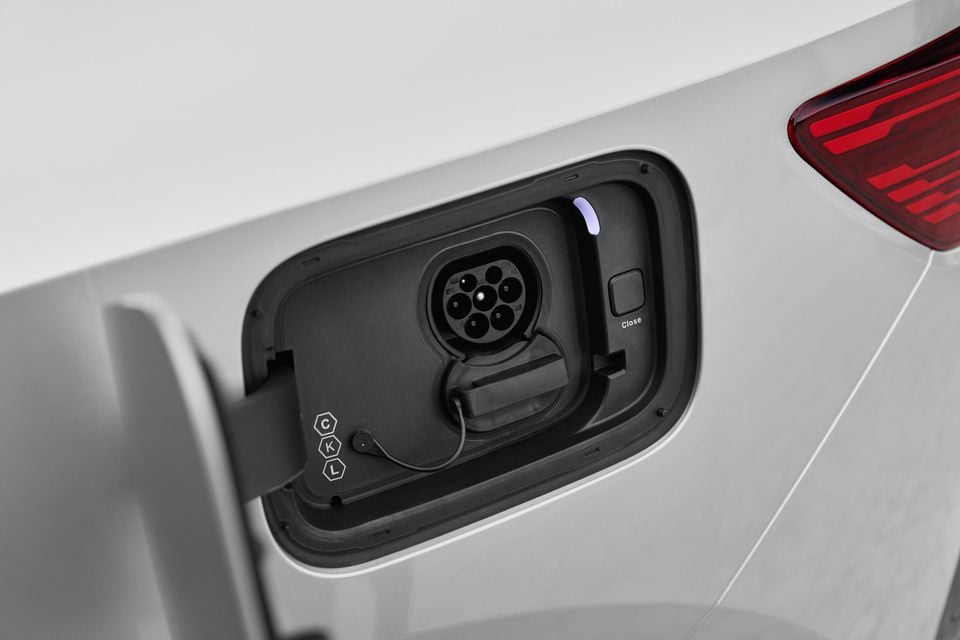 Open charging port flap on a white 2027 Polestar 4 SUV, showing the Type 2 socket beside the red tail-light
