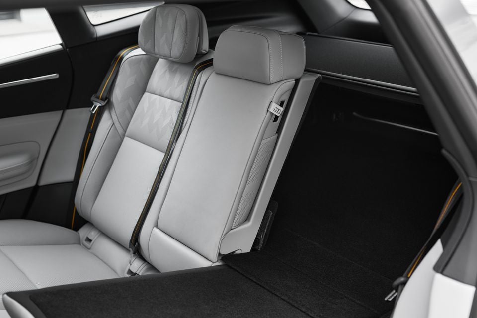 Light grey leather rear seats in a 2027 Polestar 4 SUV, with one section of the split seatback partly folded towards the carpeted cargo area