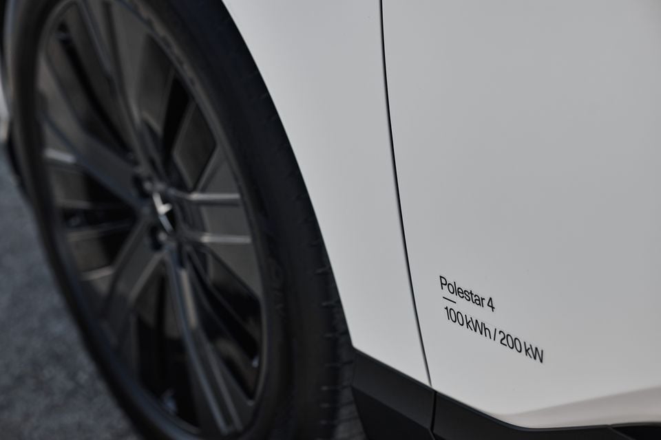 Close-up of a white Polestar 4's front wheel and side panel with a decal reading Polestar 4, 100 kWh / 200 kW