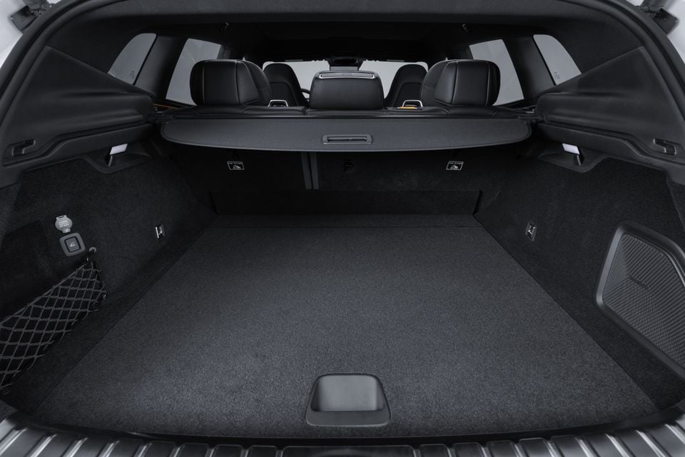 The empty boot of a 2027 Polestar 4 SUV, showing carpeted load floor, retractable cargo blind, side cargo net, and rear seats visible in the background.