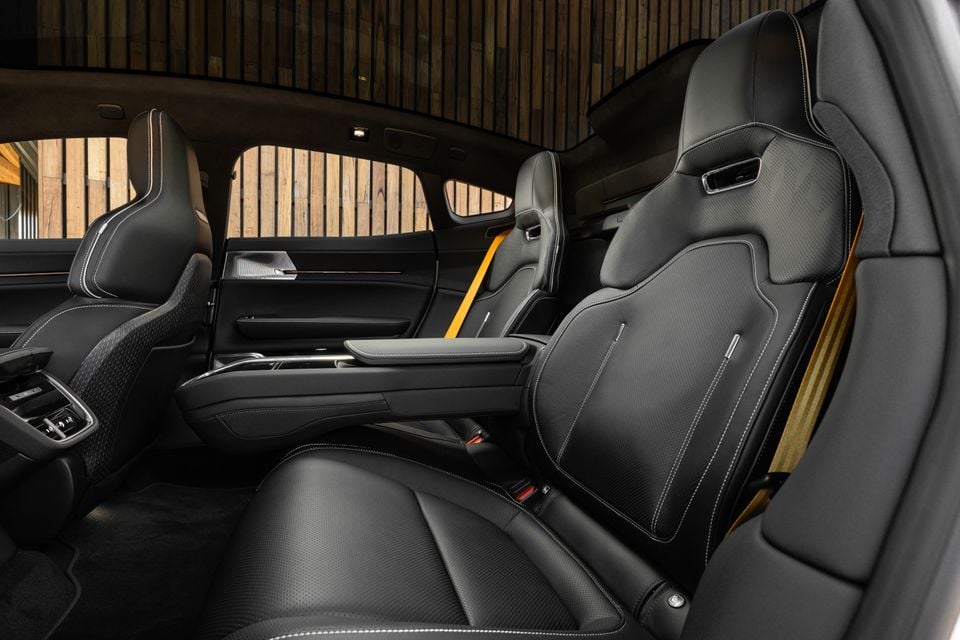 Rear seats of the 2027 Polestar 5 Performance with black leather sports seats, yellow seatbelts, a fold-down centre armrest and a panoramic glass roof